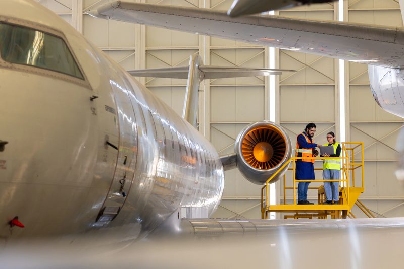Two aviation engineers inspecting the external fuselage of a commercial airplane and discussing what needs to be improved.
