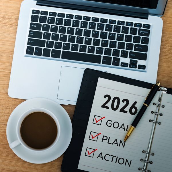 2026 planner with goals, plans, and actions checked, next to a laptop and coffee.