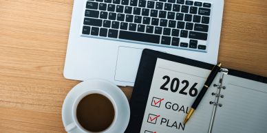 Workspace with 2026 goals checklist, laptop, and coffee.