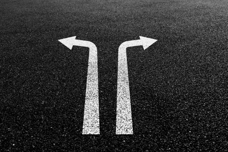 Two way arrow signs on asphalt road