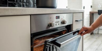 Person opening a modern oven in a kitchen.