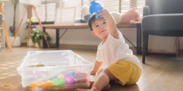 Young child playing with colorful toys on the floor.