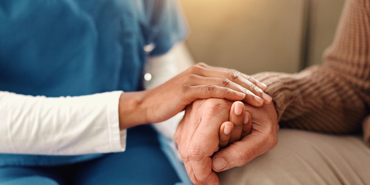 Healthcare professional comforting patient by holding hands.