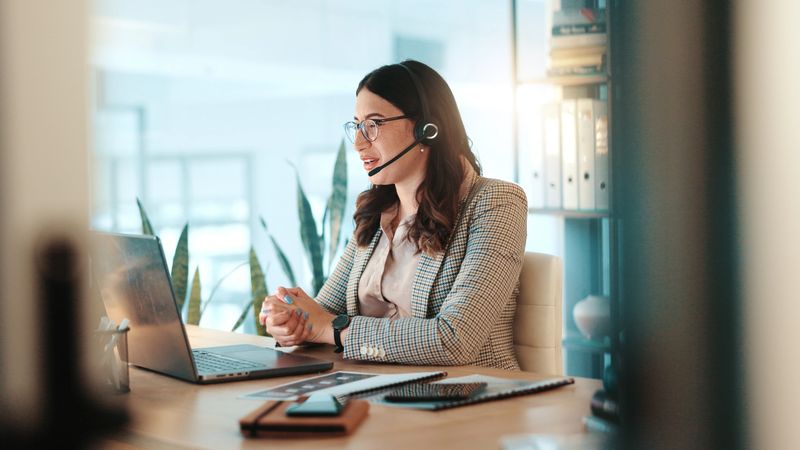 Business woman, consultant and laptop with headset for communication or online advice at office. Female person, employee or agent talking on computer for virtual assistance, app or help at workplace