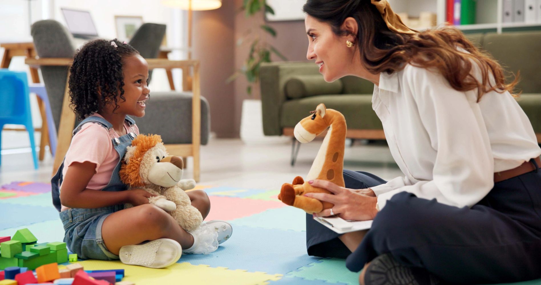 ABA therapist playing with a young girl on a colorful play mat