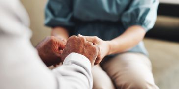 Two people holding hands in a comforting gesture.