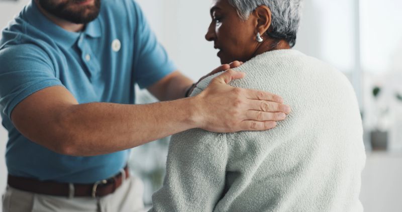 Old woman, shoulder pain and physiotherapy with man in office for consulting, health and rehabilitation. Muscle recovery, medical and support with senior patient for physical therapy and advice