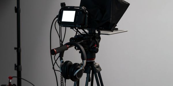 Professional video camera setup on a tripod with headphones attached.