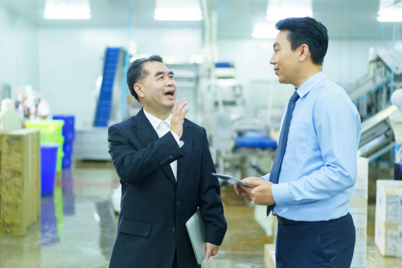 Businessman observing food factory. Asian engineer and businessman are walking around the production lines in factory and they have a business talk and discussion.