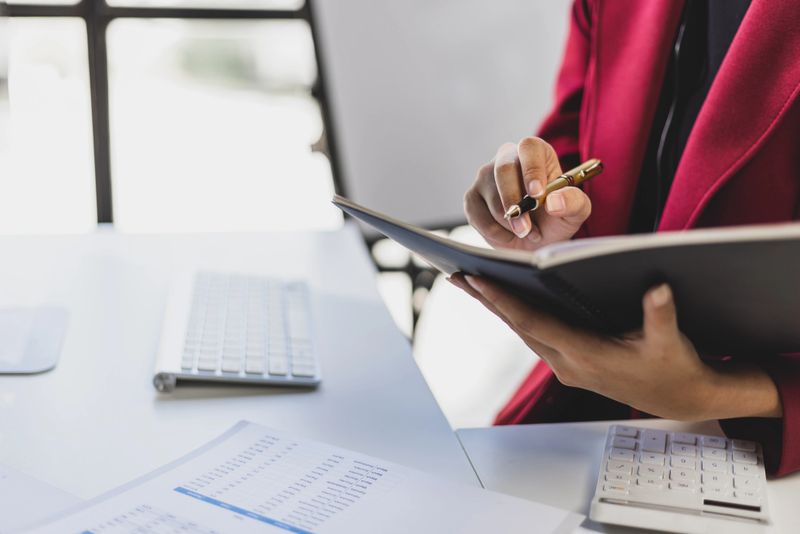 Businesswoman in office working on accounting documents and analyzing financial figures in business financial report.