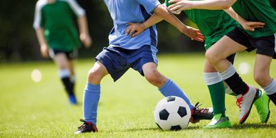 Children playing soccer on a grassy field.