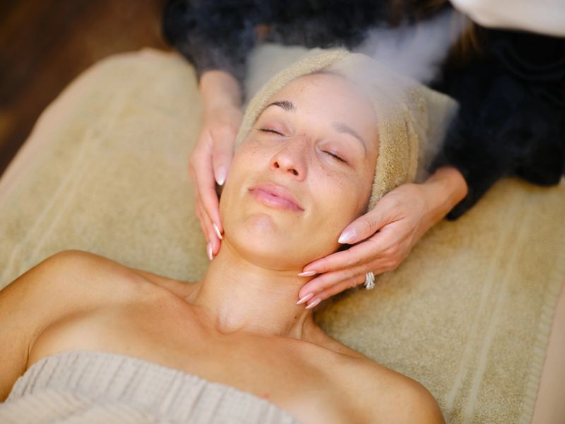 A multiracial woman in a spa receiving a beauty facial treatment.