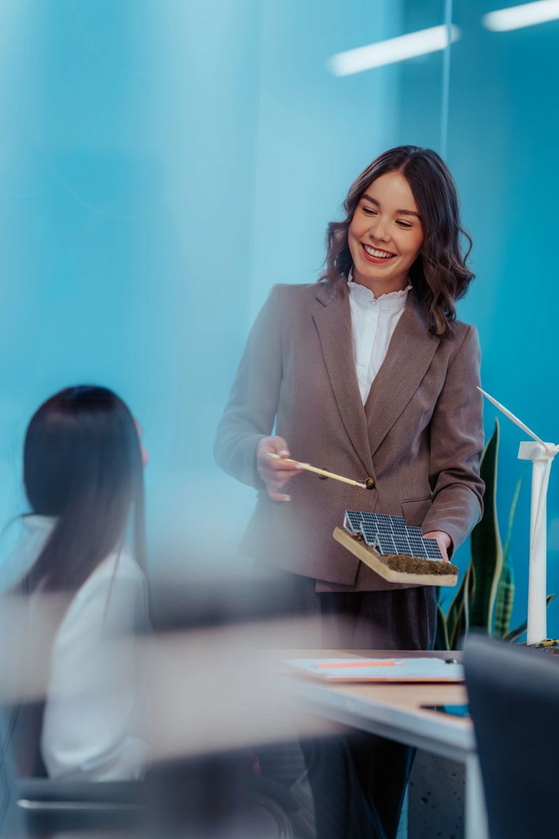Architect presenting a sustainable project with a solar panel model to a colleague in the office, showcasing eco-friendly solutions