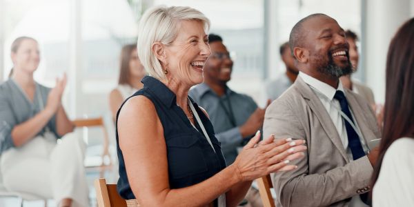 People applauding and smiling in a meeting.
