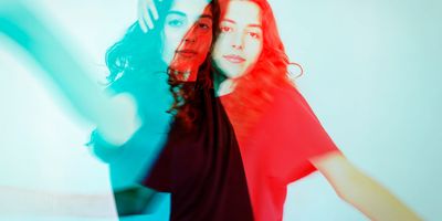 Double exposure effect with red and blue hues on a woman against a plain background.