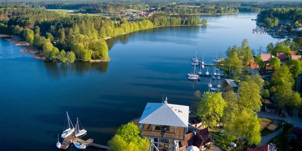 A serene lakeside with boats docked and a lookout tower under a clear sky.