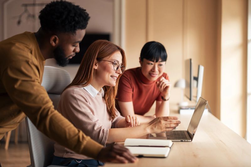 Group of professionals working together in a modern office, sharing ideas and collaborating on a project. Bright lighting and teamwork emphasize the creativity and productivity of this diverse team.