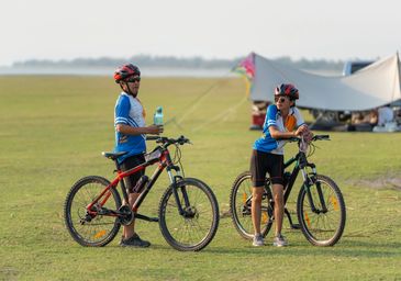 Two cyclists taking a break in an open field.