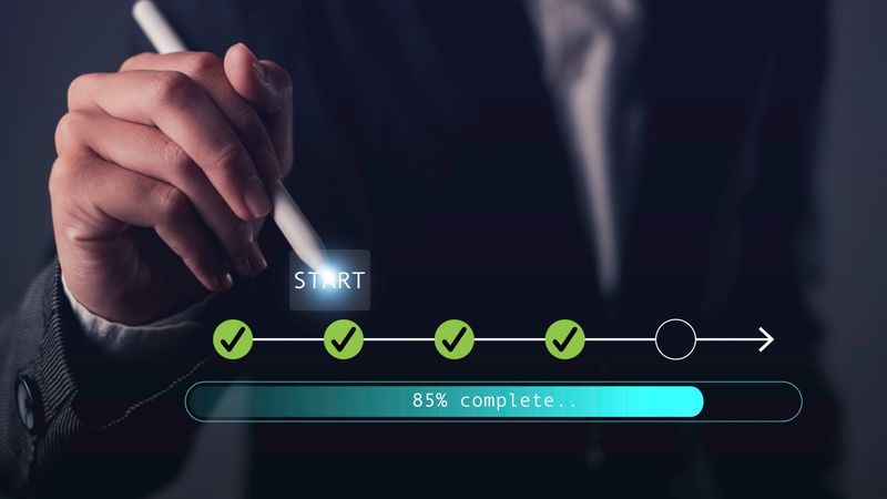 Hand holding stylus pointing at digital start button with progress bar and checklist icons, symbolizing process tracking, workflow progress, task completion, and digital planning.