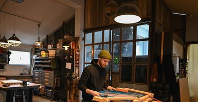 A man working on a wooden frame in a cozy workshop.