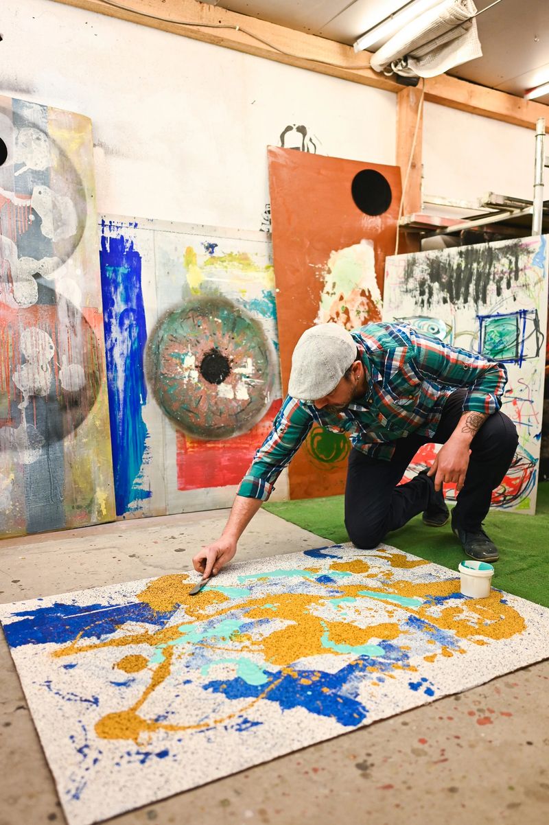 Artist painting on canvas in his workshop surrounded by art