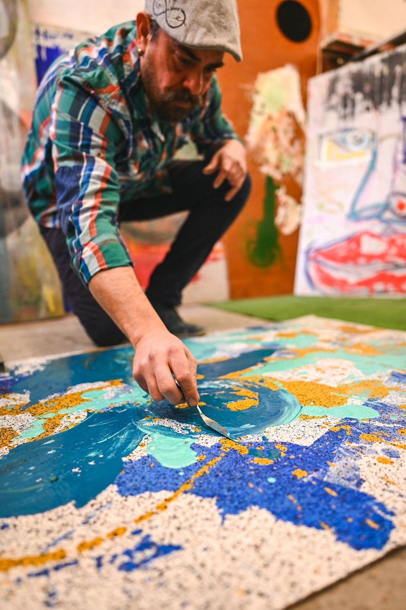 Painter using palette knife adding textures to abstract artwork