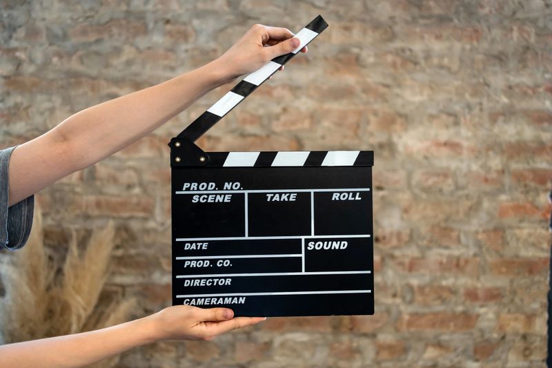 Movie clapperboard held firmly in hands on a bustling film set, signaling the start of an exciting new scene ready for filming