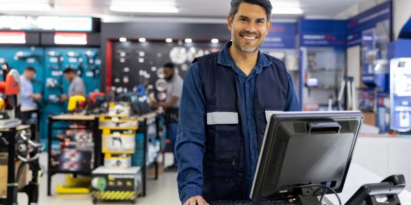 Smiling man working at a computer in a hardware store.