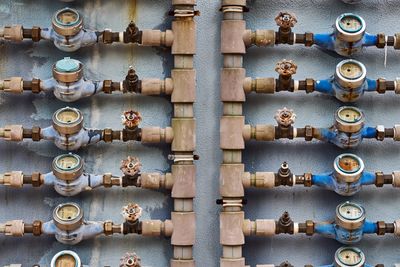 A set of old water meters and valves on a blue wall.