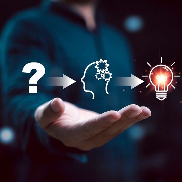 Hand presenting a concept of idea development from question to light bulb.