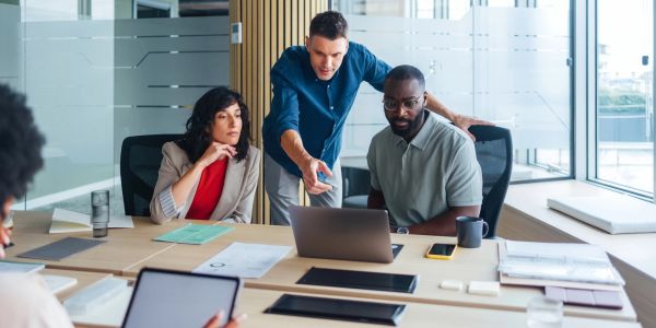 Team collaborating over a laptop in a modern office.