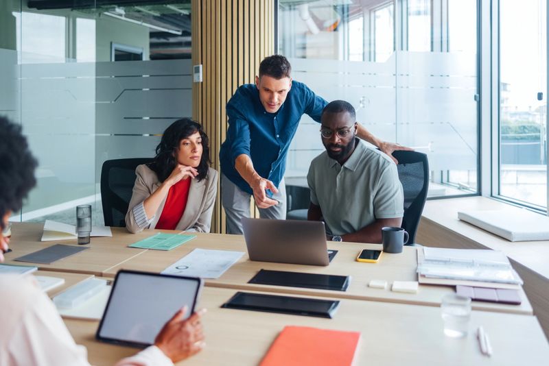 Professional team collaborating in a modern office, focused on strategic planning and teamwork. A vibrant mix of ideas, energy, and modern work environment reflect productive full engagement and brainstorming.