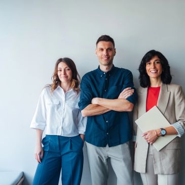 Trois jeunes professionnels souriants posant ensemble.