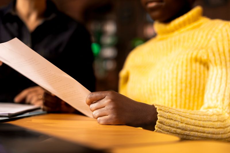 African american schoolgirl receiving personalized learning materials based on school curriculum, ensuring academic success through knowledge and research. Tutoring in a library. Close up.