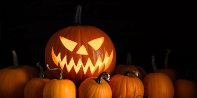 A glowing jack-o'-lantern with a scary face surrounded by small pumpkins.