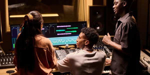 Three people in a music studio collaborating on a music project.