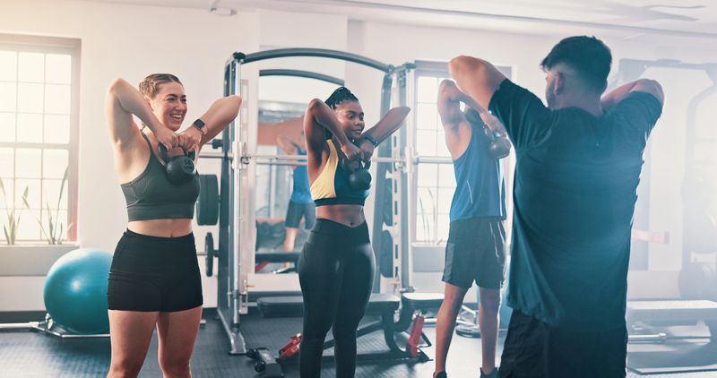 Gym, exercise and kettlebell with personal trainer, class and workout for training or fitness routine. Weightlifting, goals and target with group of sports people in health club together for muscle