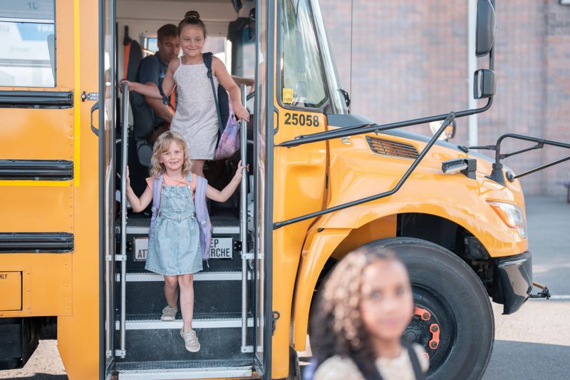 Young students stepping off a classic yellow school bus, ready to begin their educational journey. Smiling faces convey the excitement and enthusiasm associated with learning and new experiences.