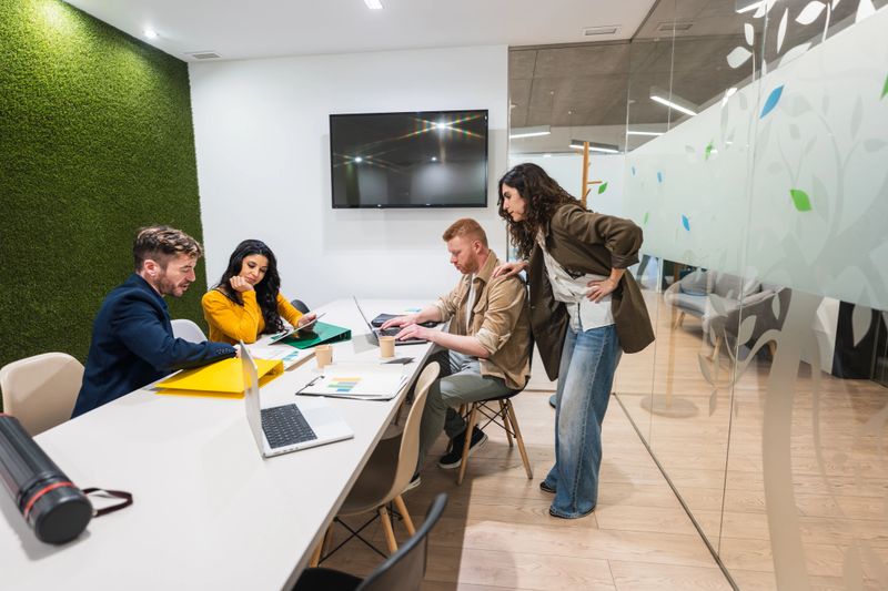 Group of young professionals working together on a project in a modern coworking office, using laptops and tablets