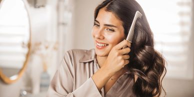 Woman happily combing her long, shiny hair in a bright room.