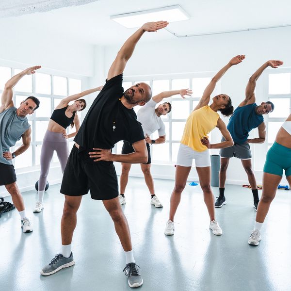 A group fitness class stretching together in a bright studio.