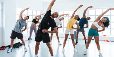 A group fitness class stretching together in a bright studio.