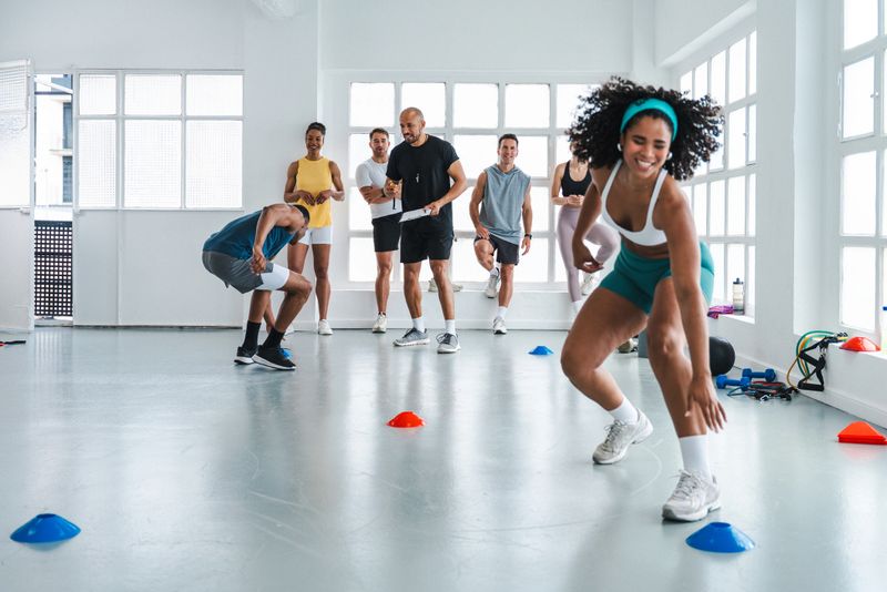 Multiethnic group of sportive people doing functional workout in training class gym multi-ethnic group attending a functional training class in a bright gym while their personal trainer takes notes