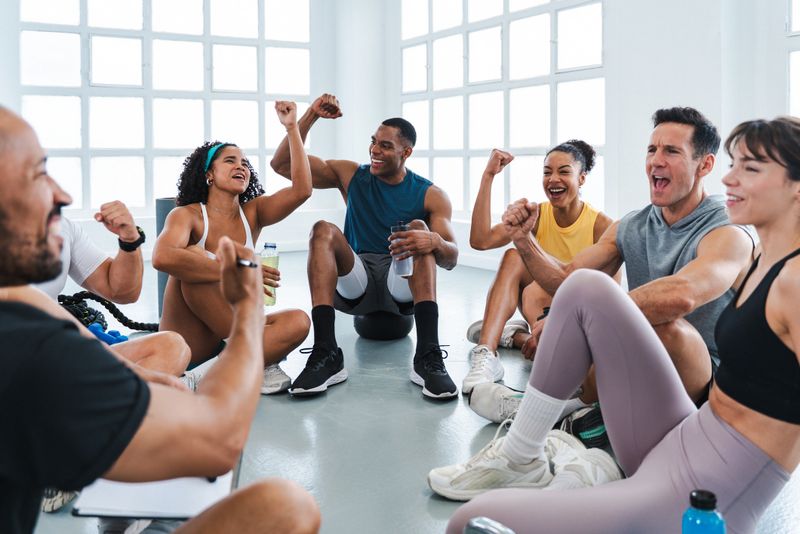 Multiethnic group of sportive people doing functional workout in training class gym athletes celebrating success in fitness circle