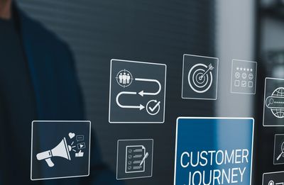 Person using laptop with digital icons about customer journey and marketing.