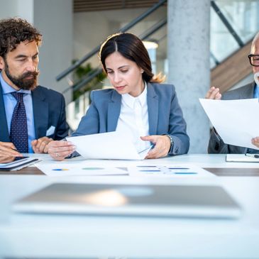 Three professionals reviewing documents in a modern office setting.