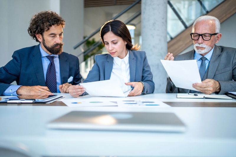 Business team engaging in a meeting, reviewing documents and analyzing charts, collaborating effectively to make informed decisions and develop strategic plans for success