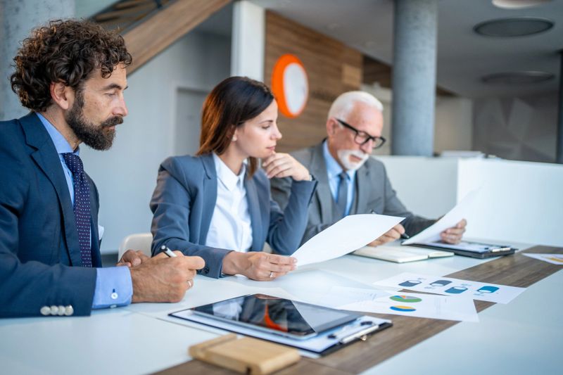 Business team collaborating in a modern office, analyzing documents and engaging in strategic discussions during a corporate meeting, emphasizing teamwork and effective decision-making