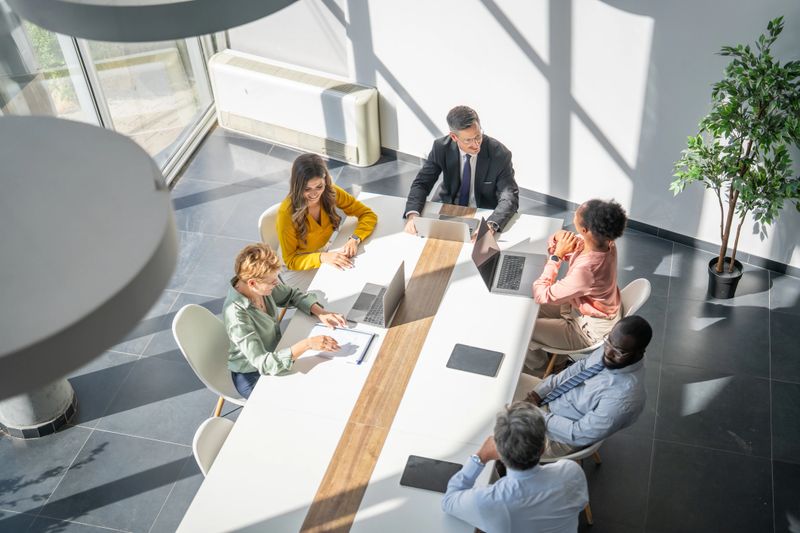 Group of business people having a meeting in a modern office, using laptops and documents, collaborating on a project