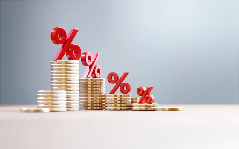 Red percentage signs over coin stacks before defocused background. Finance concept.